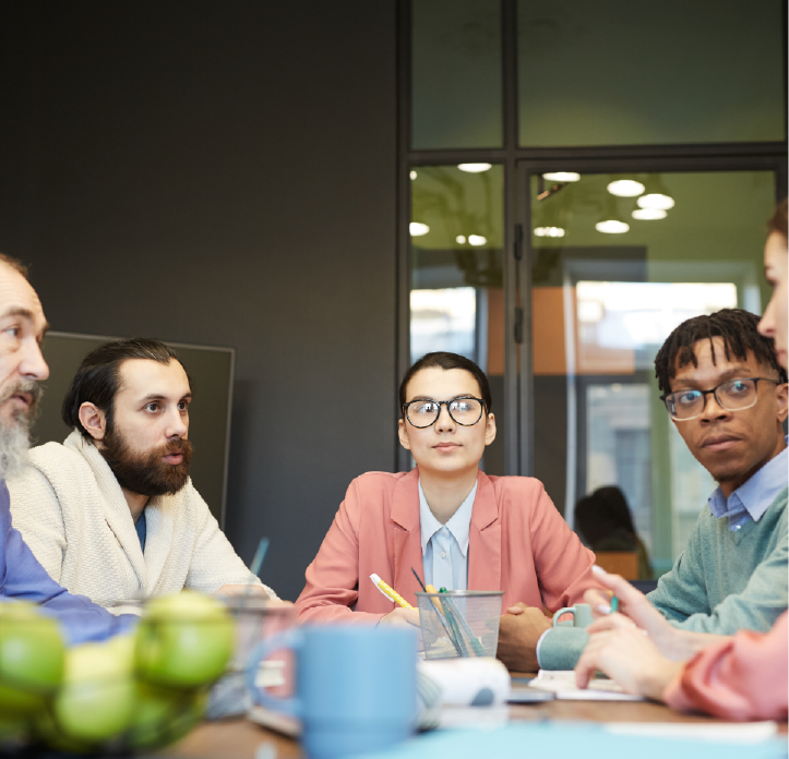 A diverse group of people engaged in a meeting, with two women and three men sitting around a table.