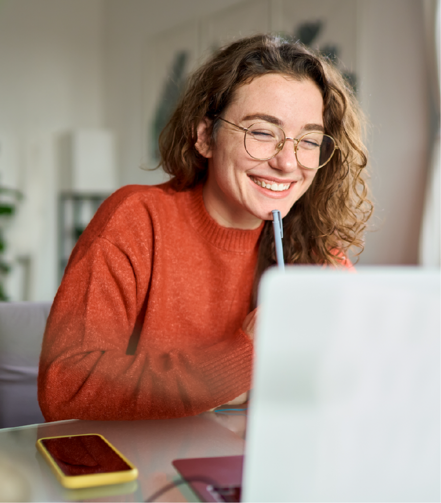 A happy woman sitting at a table with a laptop.