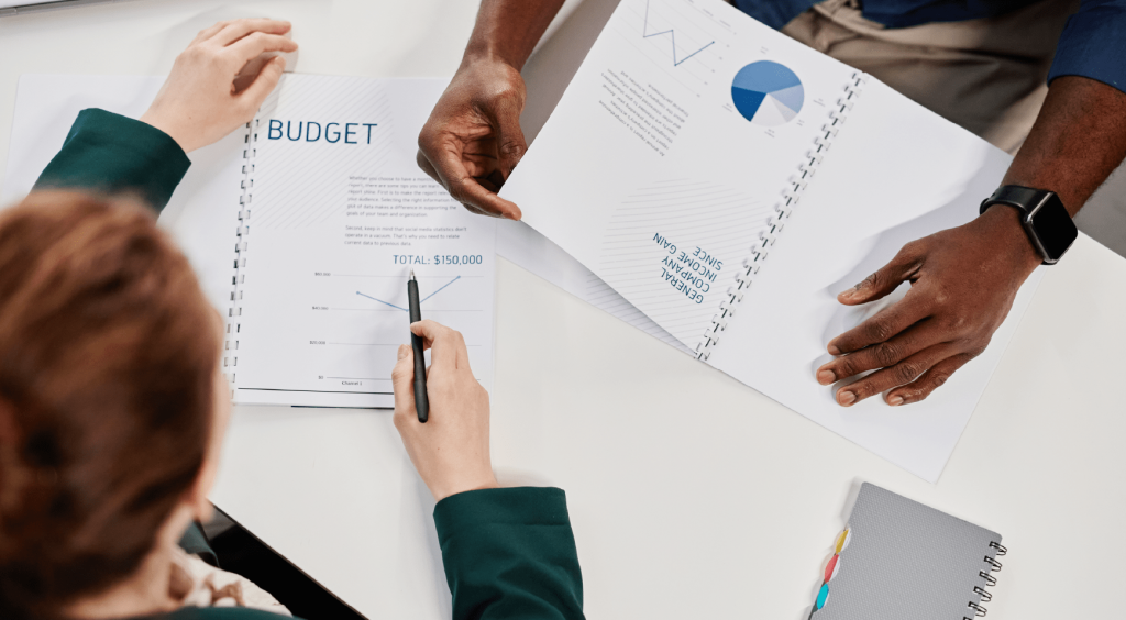 Professionals reviewing budget documents and financial charts with pie graphs and analytics on a conference table.