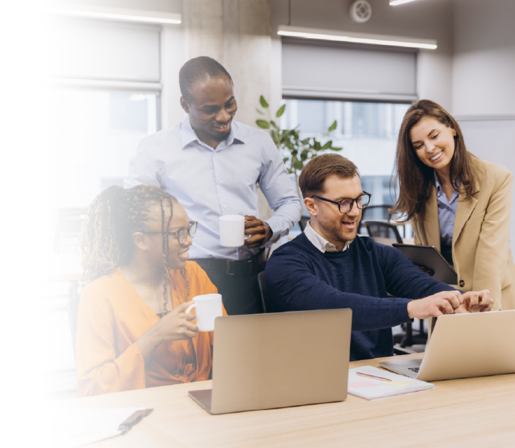 Four professionals collaborating around a laptop in a modern office.