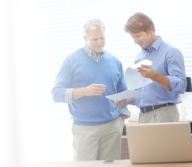 Two men reviewing and discussing documents together in an office.