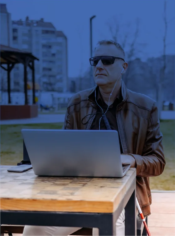 A blind man with a jacket using his laptop